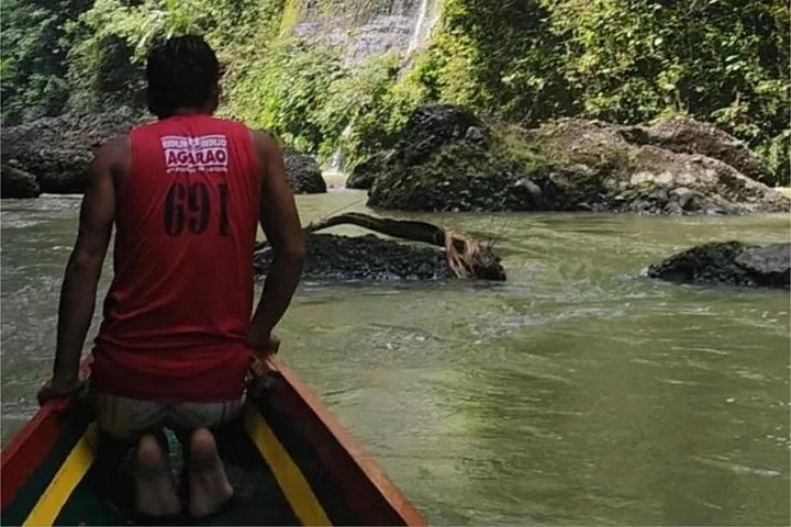 Batelier pilotant un bateau étroit dans des eaux rocheuses de rivière
